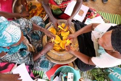 looking down on seated people around a woven bowl with food in it