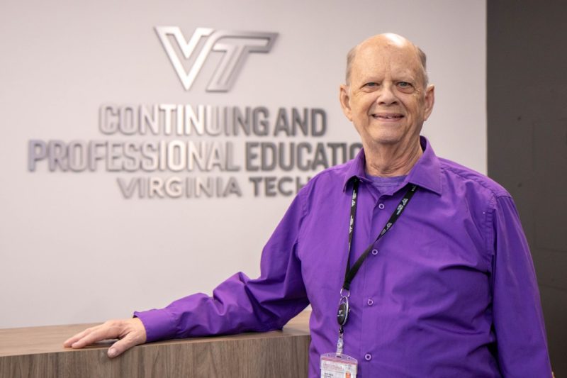 David Mitchell poses in front of the Virginia Tech Continuing and Professional Education logo displayed on a white wall.