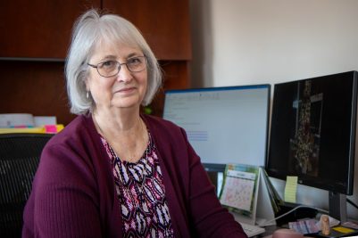 Martha Franklin sits at a wooden desk with monitors behind her in the background.